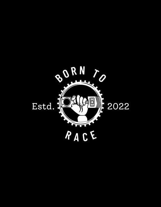 Ez a kép egy markáns, versenyinspirált dizájnt mutat be, középpontjában egy ököl, amit egy abroncs vesz körül, és a "BORN TO RACE" felirat díszíti, alattuk az "Estd. 2022" szöveggel.